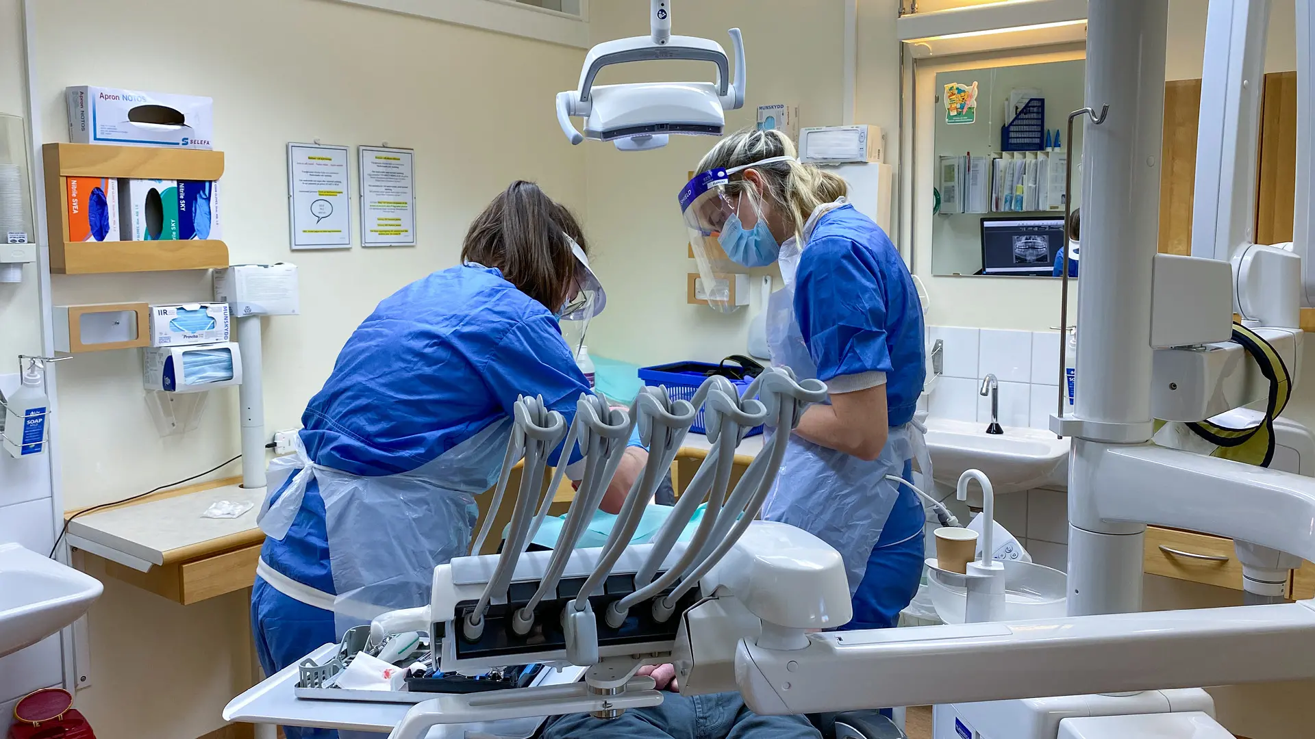 Tandläkaren utför en parodbehandling tillsammans med tandsköterska